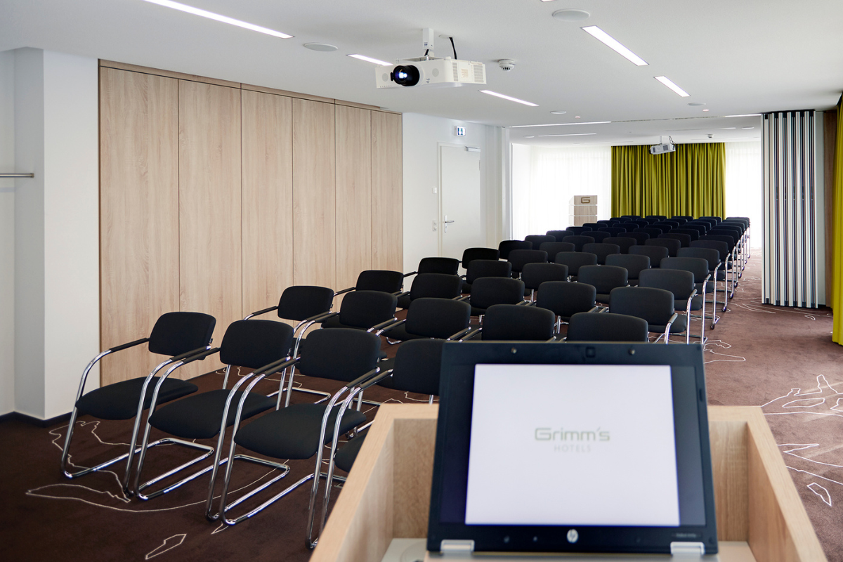 Konferenzraum im Grimm's Hotel am Potsdamer Platz in Berlin mit vielen Stühlen, einem Projektor und der gesamten Technik, die für Geschäftstreffen in Deutschland benötigt wird