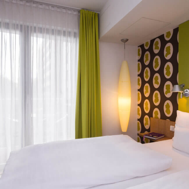 Galerie Mitte. Ein Hotelzimmer mit Doppelbett.